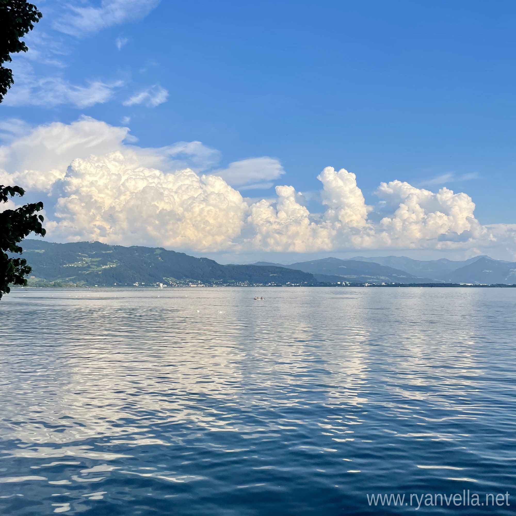 Cumulus clouds building over a lake, seen from a wooded shoreline